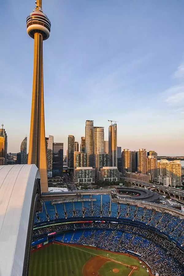 CN Tower in Toronto, Canada with Rogers Centre Stadium filled with Toronto Blue Jay fans in the foreground